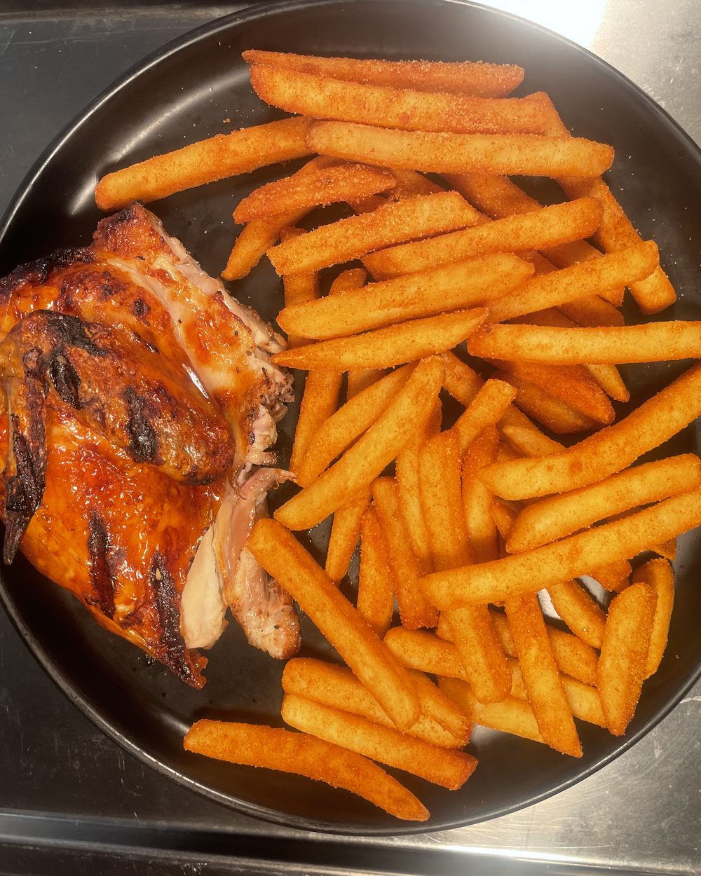 Half a chargrilled chicken with seasoned chips, char marks across the skin